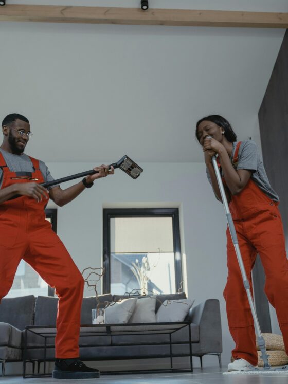 Cleaning Business: Man and woman cleaning in orange jumpsuits and playfully smiling at one another