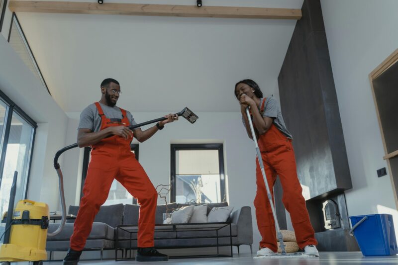Cleaning Business: Man and woman cleaning in orange jumpsuits and playfully smiling at one another