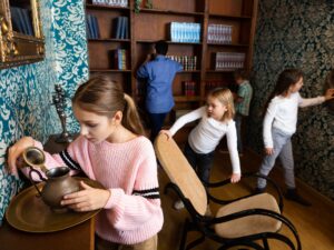 Escape Room: Interested tween girl examining ancient kettle in quest room stylized as old library