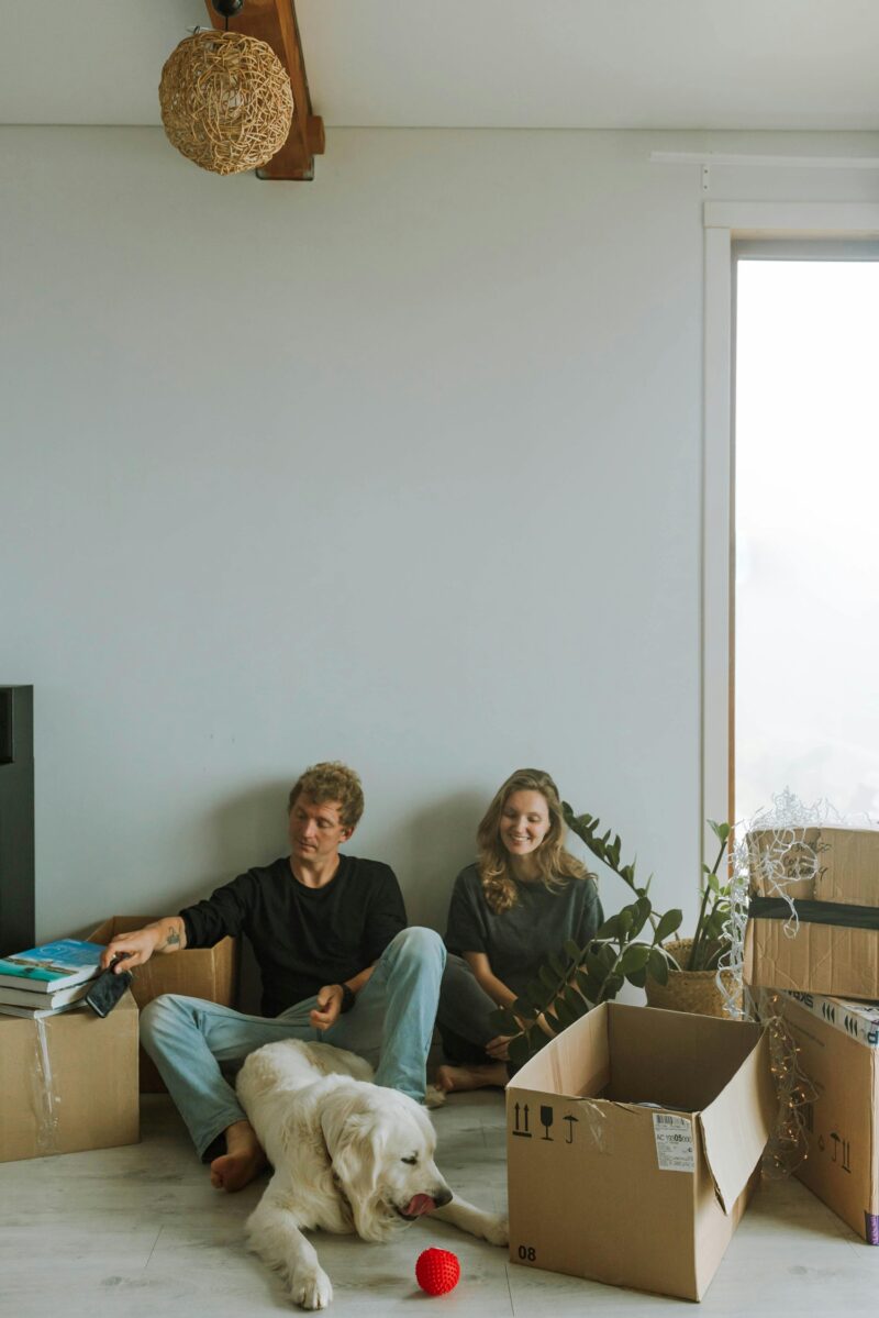 Moving with Pets: Couple sitting on the floor with their dog surrounded by boxes
