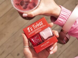 Nails.INC’s It’s Topless: Woman's hand holding two nail polishes and a drink with a straw