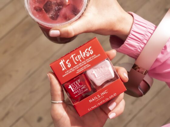 Nails.INC’s It’s Topless: Woman's hand holding two nail polishes and a drink with a straw