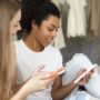 AI: Two women sitting side by side on their cell phones