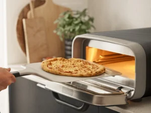 Ooni: Pizza oven on a counter top with pizza sliding in