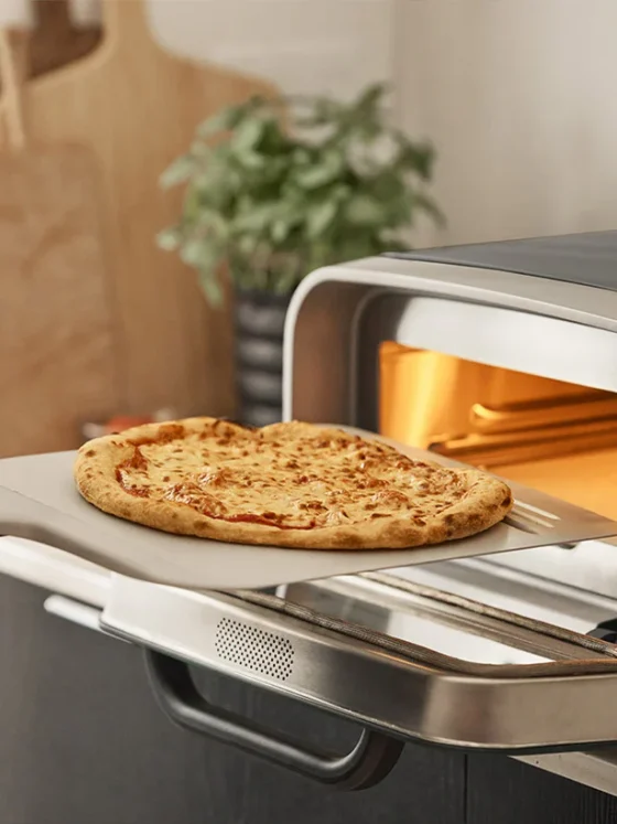 Ooni: Pizza oven on a counter top with pizza sliding in