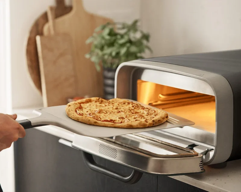Ooni: Pizza oven on a counter top with pizza sliding in