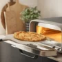 Ooni: Pizza oven on a counter top with pizza sliding in