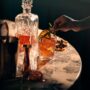 Whisky Tasting Party: woman's hand putting rosemary sprig into a glass of whisky - decanter nearby