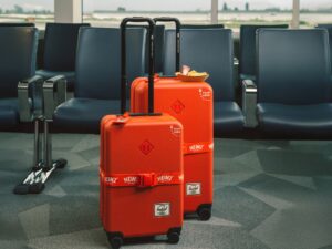 Herschel x HEINZ: Large and carry on red luggage in front of airport seats