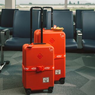 Herschel x HEINZ: Large and carry on red luggage in front of airport seats