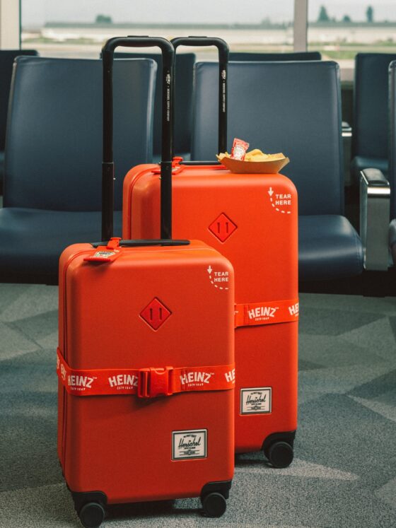 Herschel x HEINZ: Large and carry on red luggage in front of airport seats