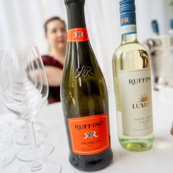 Prosecco: A bottle of Ruffino Prosecco and a bottle of Pinot Grigio on a table in the foreground with a person in the background