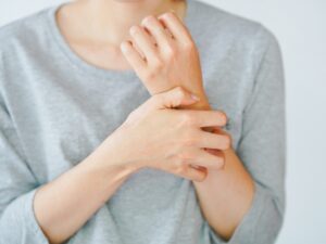 Zax's Original: A woman scratching her arm, experiencing an allergic reaction or being stung by an insect. Skin disease concept.