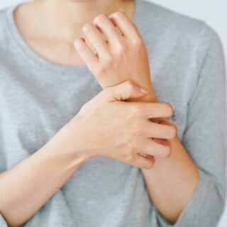 Zax's Original: A woman scratching her arm, experiencing an allergic reaction or being stung by an insect. Skin disease concept.