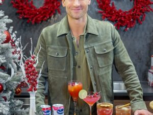 Holiday Ritual: Actor Andrew Walker behind a bar that is decorated with holiday decor with Ocean Spray Cans and cocktails in front of him