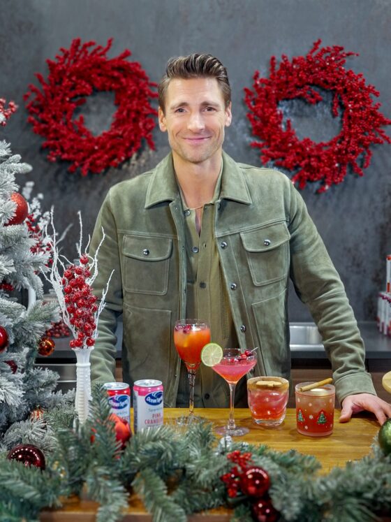 Holiday Ritual: Actor Andrew Walker behind a bar that is decorated with holiday decor with Ocean Spray Cans and cocktails in front of him
