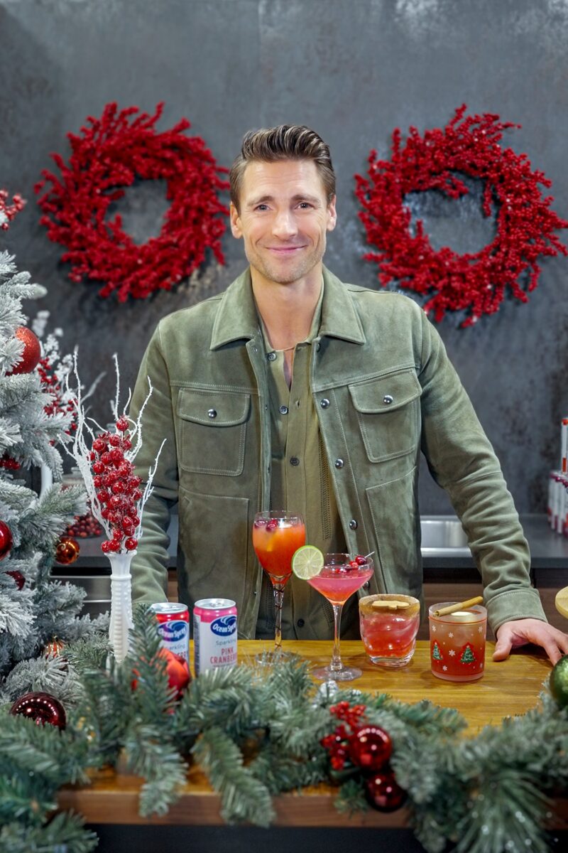 Holiday Ritual: Actor Andrew Walker behind a bar that is decorated with holiday decor with Ocean Spray Cans and cocktails in front of him