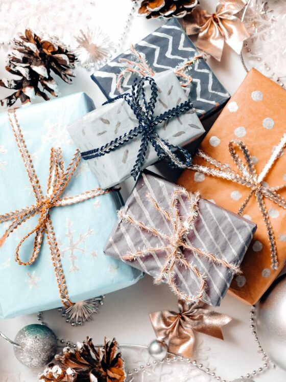 Gifts for Everyone on Your List: Holiday gifts beautifuly wrapped with pine cones and ornaments surrounding them