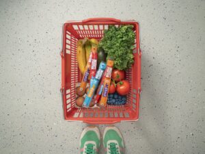 Protein for Women: Grocery basket with produce and Mighty Protein sticks next to women's sneakers