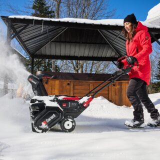 Snow Blowers: Woman pushing snowblower in front of her home