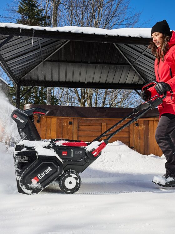 Snow Blowers: Woman pushing snowblower in front of her home