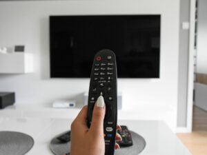 Digital Entertainment: Woman's hand holding a remote control at a TV set