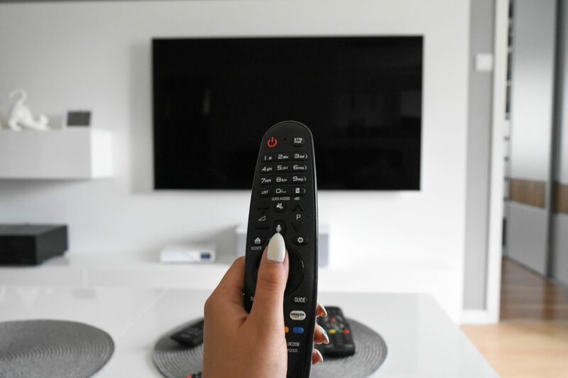 Digital Entertainment: Woman's hand holding a remote control at a TV set