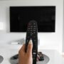 Digital Entertainment: Woman's hand holding a remote control at a TV set