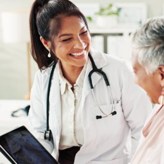 Family Doctor: Mature woman, doctor and tablet for healthcare, support or conversation with checkup appointment in office. Female person, medical professional and diagnosis talk for senior patient at clinic