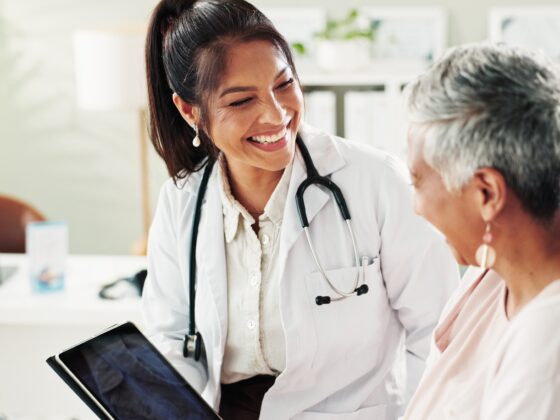 Family Doctor: Mature woman, doctor and tablet for healthcare, support or conversation with checkup appointment in office. Female person, medical professional and diagnosis talk for senior patient at clinic