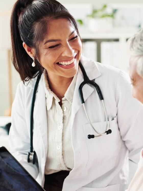 Family Doctor: Mature woman, doctor and tablet for healthcare, support or conversation with checkup appointment in office. Female person, medical professional and diagnosis talk for senior patient at clinic