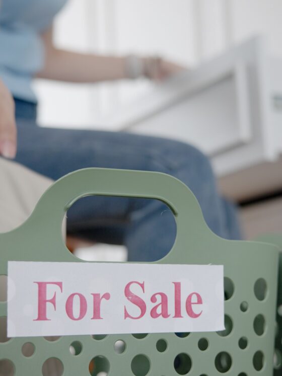 Poshmark Closet: Woman listing items with a for sale bin next to her desk