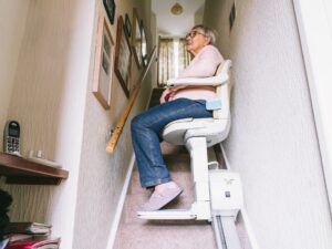 Stairlift: Senior woman using automatic stair lift on a staircase at her home.