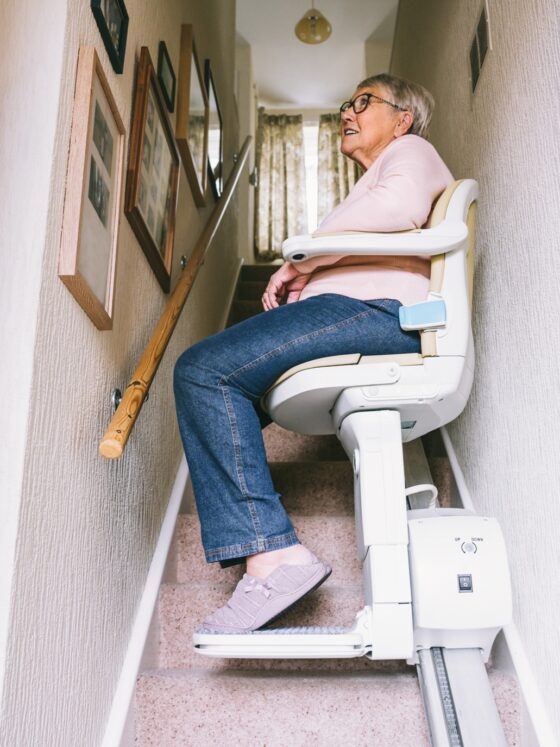 Stairlift: Senior woman using automatic stair lift on a staircase at her home.
