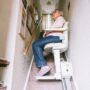 Stairlift: Senior woman using automatic stair lift on a staircase at her home.