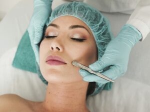 Facial Rejuvenation: Woman lying down with surgical cap on as someone is doing a procedure.