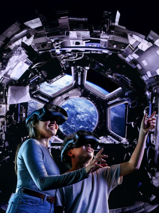 Space Explorers: The Infinite: Woman and Child with Space in the background wearing VR goggles