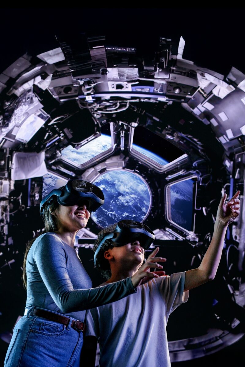 Space Explorers: The Infinite: Woman and Child with Space in the background wearing VR goggles