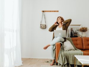 Unwind Online: A woman in bare feet perched on a sofa with her laptop and on her phone