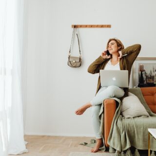 Unwind Online: A woman in bare feet perched on a sofa with her laptop and on her phone
