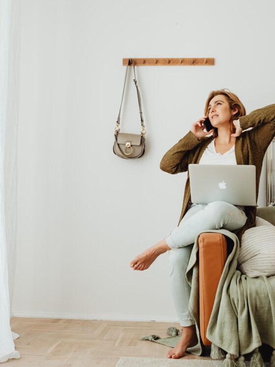 Unwind Online: A woman in bare feet perched on a sofa with her laptop and on her phone