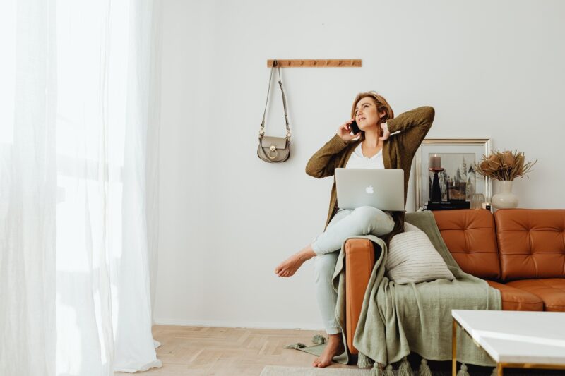 Unwind Online: A woman in bare feet perched on a sofa with her laptop and on her phone