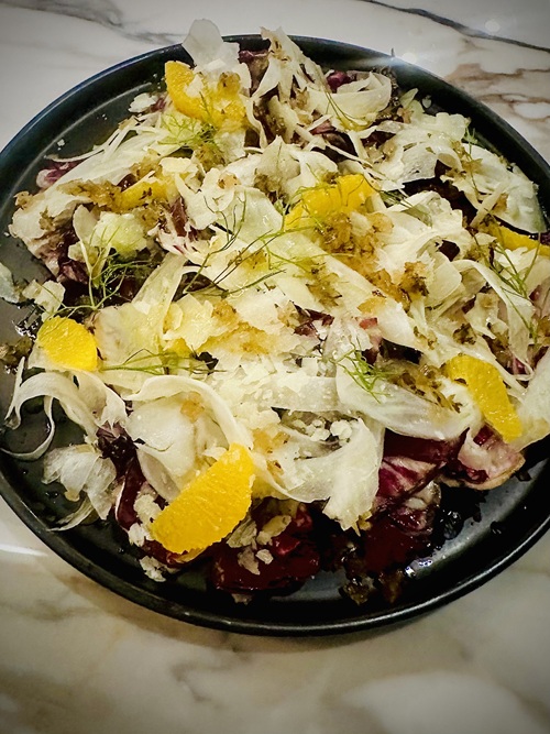 Vivo Avanti: Insalata di Radicchio with honey vinaigrette, shaved fennel, orange, shaved Grana Padano on a black plate