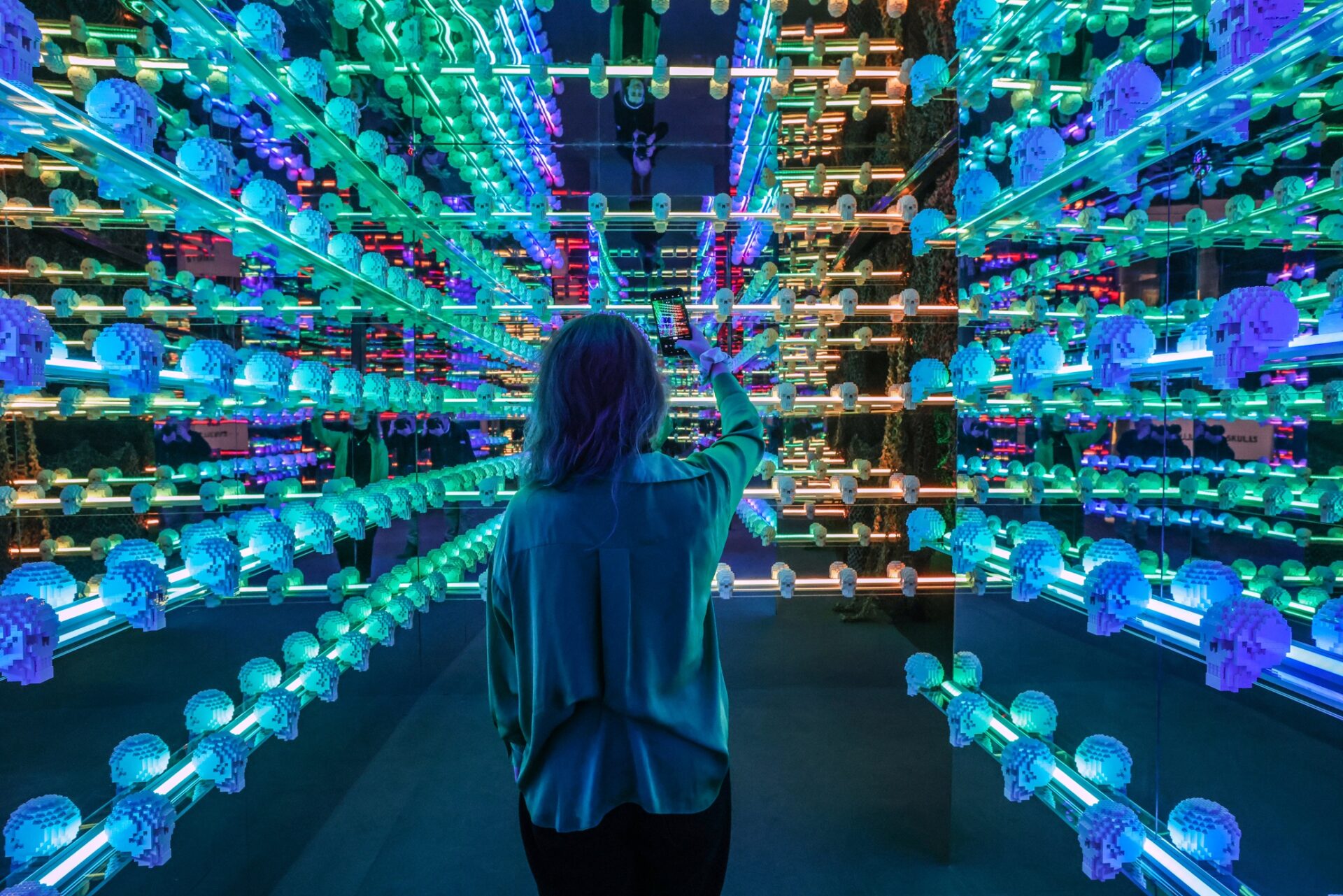 Art of the Brick: Woman in a room filled with blue lit LEGO Skulls
