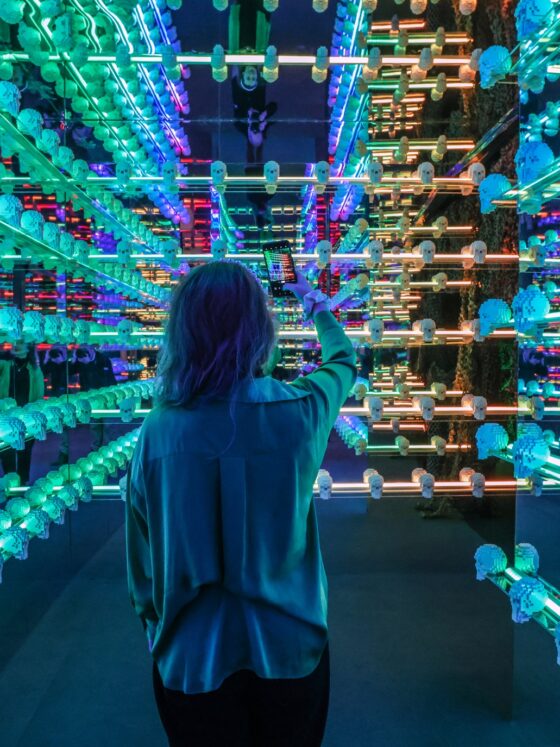 Art of the Brick: Woman in a room filled with blue lit LEGO Skulls