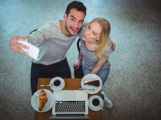Digital Photos: Smiling young couple taking selfie while having coffee in a cafe