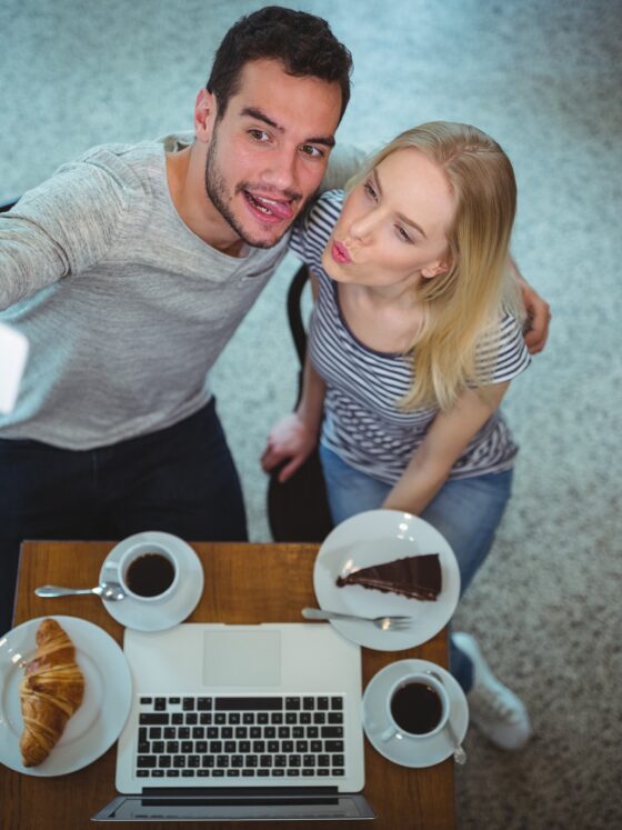 Digital Photos: Smiling young couple taking selfie while having coffee in a cafe