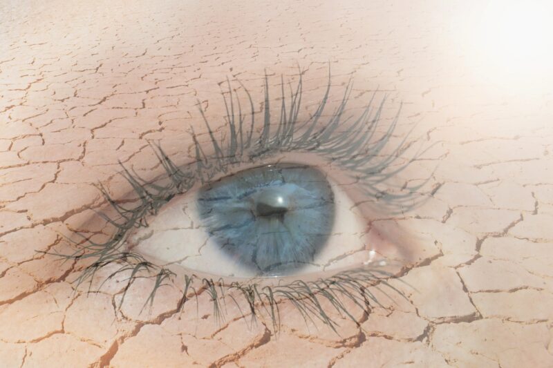 Eye Health: Double exposure of human eye in dry land on the background.