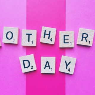 Gifts Your Mom Will Love: Mother's Day spelled out in Scrabble Tiles against a pink striped background