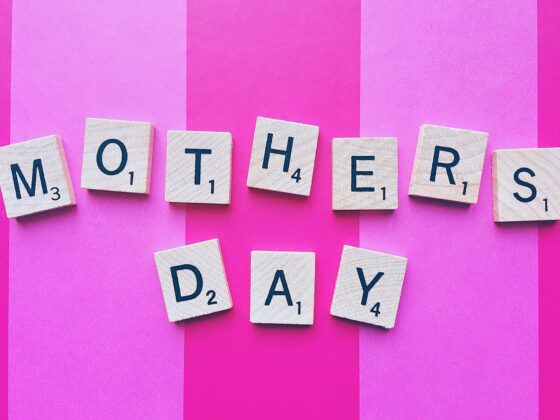 Gifts Your Mom Will Love: Mother's Day spelled out in Scrabble Tiles against a pink striped background